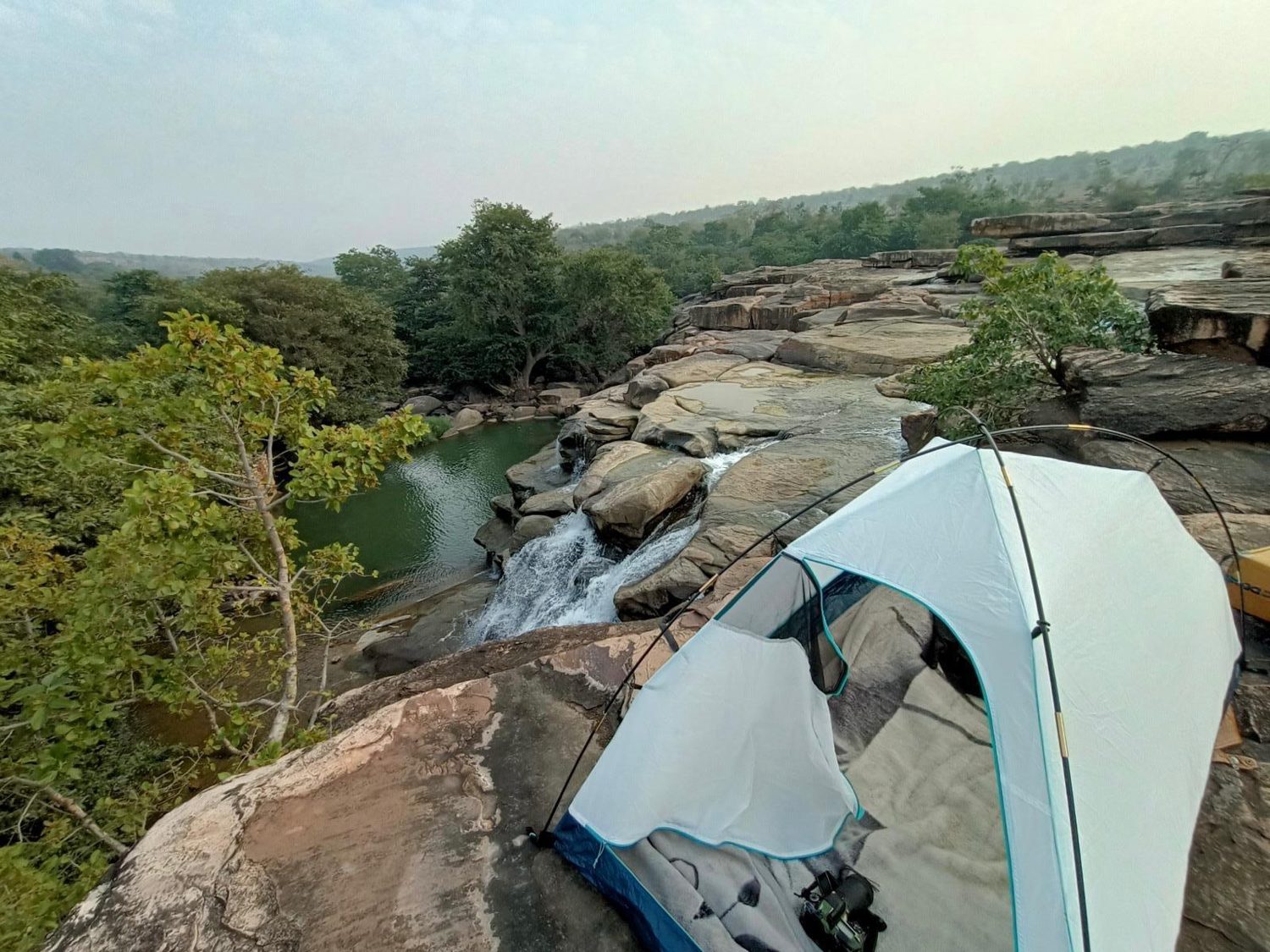 A tent pitched above a forest stream